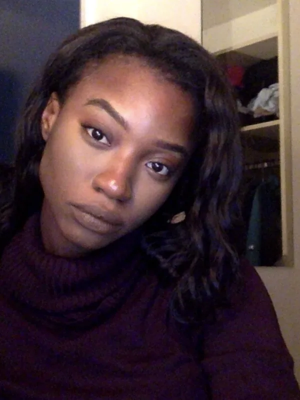 Femme aux cheveux noirs en pull col roulé, regardant l'objectif devant un placard ouvert.