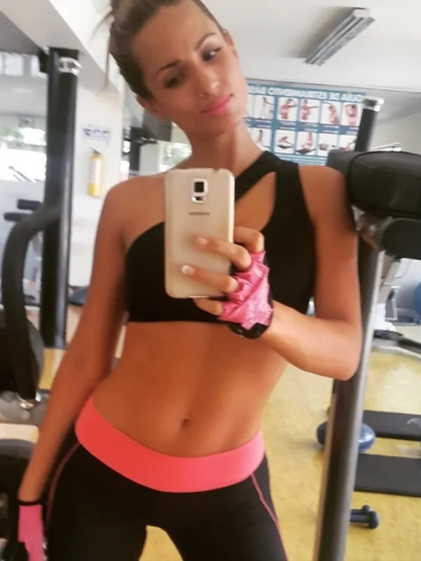 Portrait d'une femme en tenue de sport prenant un selfie dans un miroir d'une salle de gym.